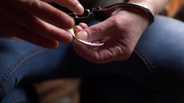 Prisonnier menotté roulant une cigarette — Video