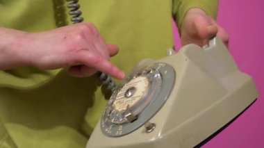 Bir numarayı aramak için klasik telefon kullanan bir kadın.