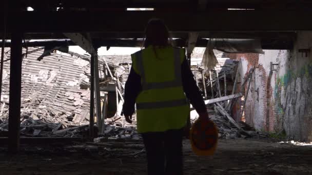 Silueta de trabajador camina a través de sitio de demolición peligrosa — Vídeos de Stock