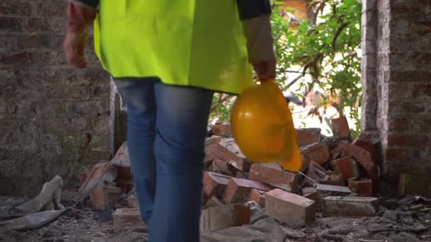 Trabalhador em edifício demolido com chapéu duro andando através de detritos — Vídeo de Stock