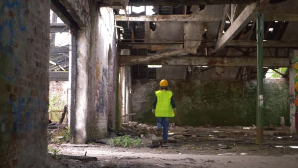 Arbetare i hård hatt promenader genom riven byggnad — Stockvideo