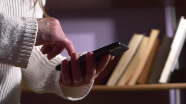 Femme utilisant un smartphone avec étui bibliothèque en arrière-plan — Video
