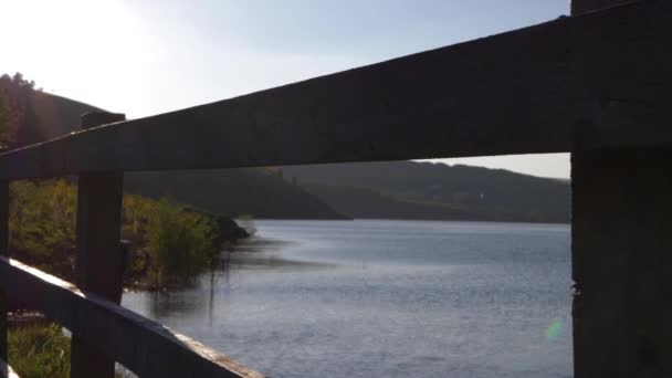 木製の柱の眺めを通して水の丘や湖 — ストック動画