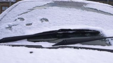 Araba silecekleri soğuk kış sabahında karı silip süpürür.