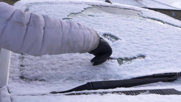 Малюнок усміхненого обличчя на вітровому склі автомобіля, вкритому снігом — стокове відео