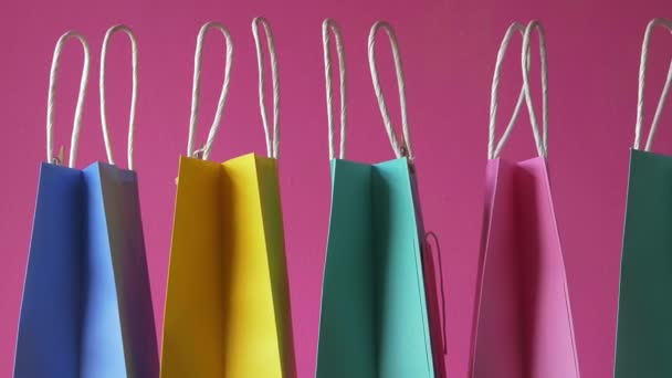 Ligne de sacs-cadeaux colorés sur fond rose plan moyen — Video