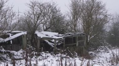 Old rickety wooden sheds in winter scene after snowfall