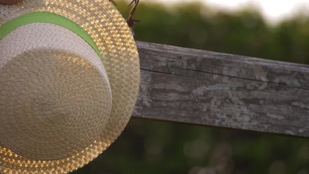 Straw hat hangs from a country wooden gate — Stock Video