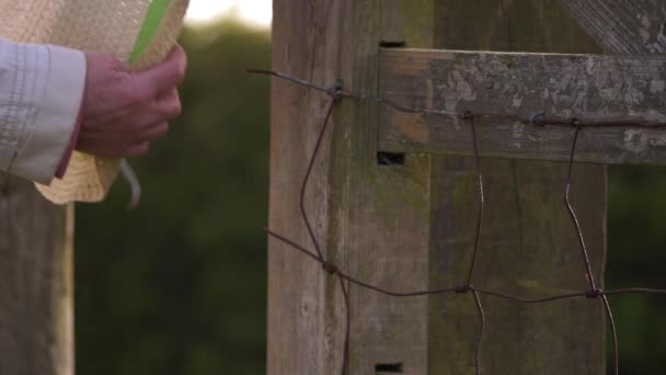 Mujer cuelga sombrero de paja en puerta de campo de madera — Vídeos de Stock
