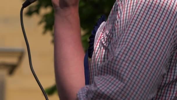 Политик, носящий розетку, произносит речь с микрофоном — стоковое видео