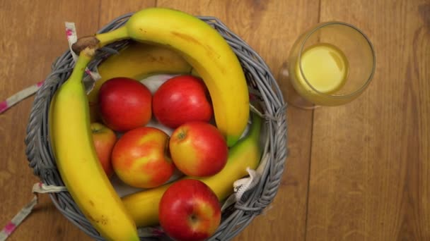 Maçãs e bananas em uma cesta com suco de laranja — Vídeo de Stock