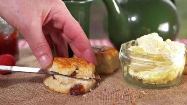 Hand slicing scone with fresh clotted cream — Stock Video