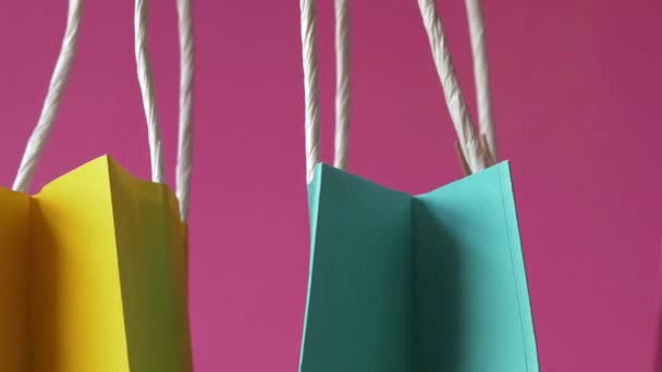 Fila de coloridas bolsas de regalo sobre fondo rosa de cerca — Vídeos de Stock