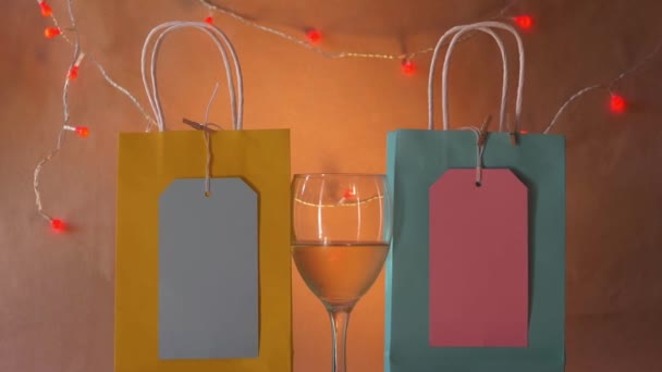 Sacs cadeaux et verre de vin blanc sur fond chaud — Video