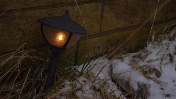 Linterna de jardín al atardecer mientras cae nieve — Vídeos de Stock