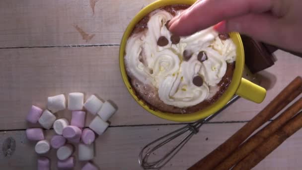 Mão polvilha coberturas na bebida de chocolate quente — Vídeo de Stock