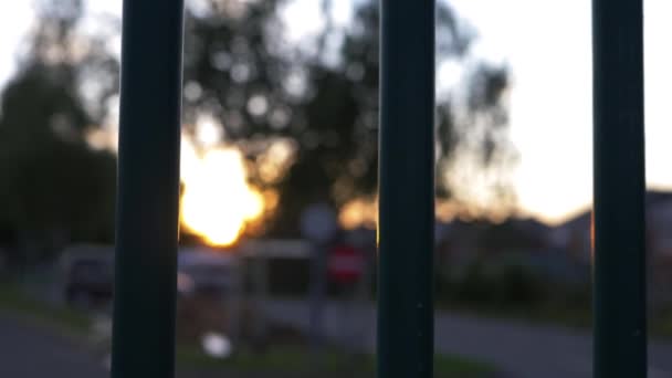 Pôr do sol na cena urbana através da vista do portão de metal — Vídeo de Stock