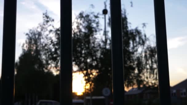 Zonsondergang op stedelijke scène door het oog van metalen poort — Stockvideo