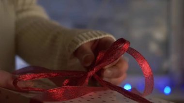 Bokeh ışıkları arka planda olan bir kadın Noel hediyesini açıyor