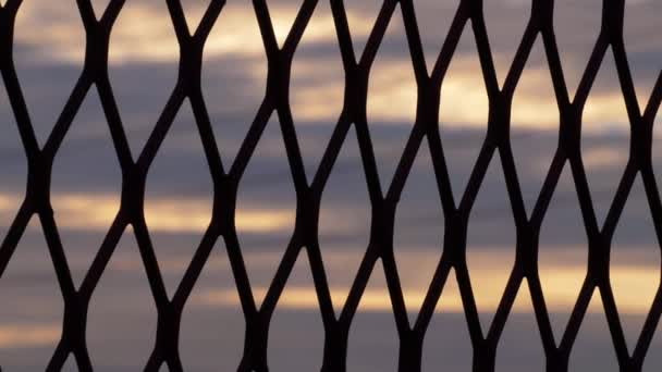 Sunset sky through view of fence in silhouette — Stock Video