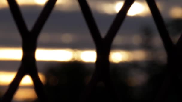 Vista de la puesta de sol al atardecer a través de la vista de la cerca en la silueta — Vídeos de Stock