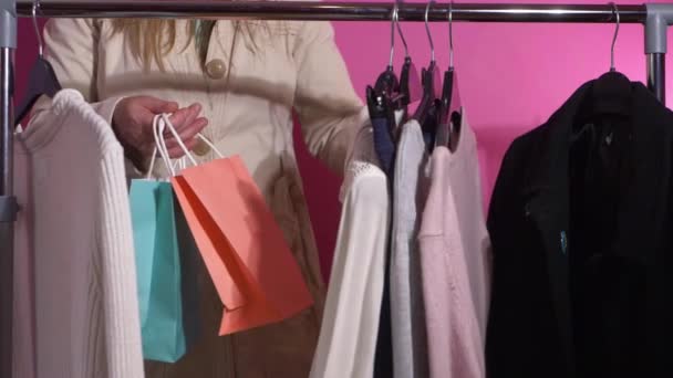 Mulher com sacos de compras em olhando através de roupas na boutique — Vídeo de Stock