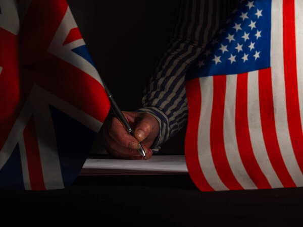 Ручное подписание торгового соглашения с американским флагом США и британским Союзом Джек среднего выстрела избирательный фокус