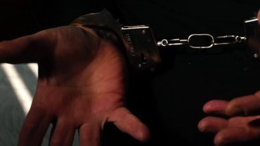 Tutuklandıktan sonra elleri kelepçeleyip zoom atışı yap. Seçici odaklan.