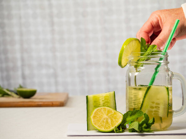 Making healthy cucumber mint and lime refreshing detox drink medium shot selective shot