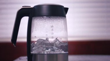 Sıcak su cam çaydanlıkta kaynıyor. 4k ağır çekim seçici odak noktası.