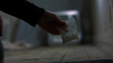 Terk edilmiş evde uyuşturucu torbası tutan bir uyuşturucu satıcısı. 4K 'lık seçici odak noktasını kapat.