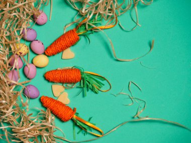 Paskalya ekran yumurta havuç ve saman orta çekim yeşil arkaplan düz seçici odak yatıyordu