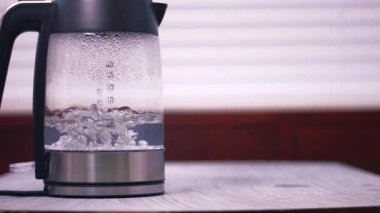 Cam çaydanlıkta kaynayan sıcak su geniş çaplı zoom yavaş çekim seçici odak noktası