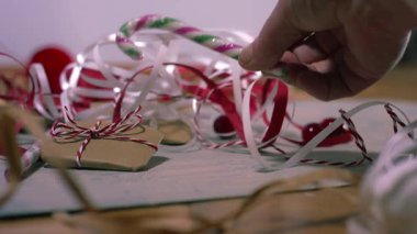 Noel hediyesi kurdele ve şeker kamışlı eller 4K yavaş çekim seçici odak noktasını kapatın.