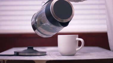 Çaydanlıktan kupaya sıcak su dökülüyor. 4 km yavaş çekim seçici odak noktası.