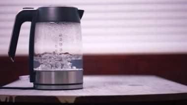 Cam çaydanlıkta kaynayan sıcak su geniş çaplı 4k yavaş çekim seçici odak noktası