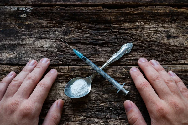 Jeringa macho adicto y heroína en una cuchara en forma de cruz — Foto de Stock