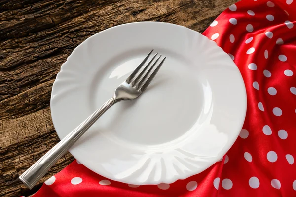 Placa branca vazia com um garfo em um guardanapo vermelho na mesa — Fotografia de Stock