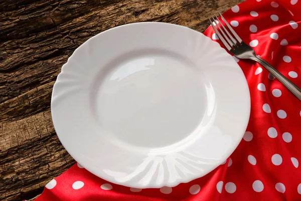 Placa branca vazia em um guardanapo vermelho na mesa — Fotografia de Stock