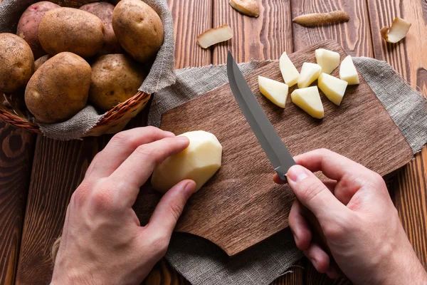 Mann schneidet geschälte Kartoffeln — Stockfoto