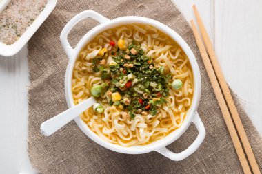 Beyaz bir tabakta sebze ve yemek çubukları ile anlık erişte