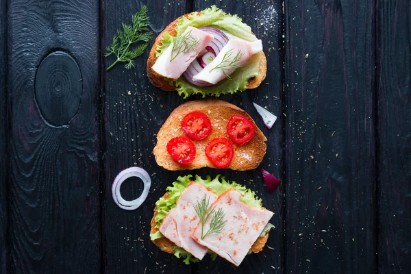 Et ve sebze siyah bir arka plan ile farklı sandviç