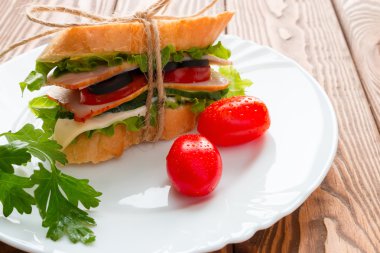 Beyaz bir plaka üzerinde beyaz ekmek maydanoz ve kırmızı kiraz domates ile sandviç