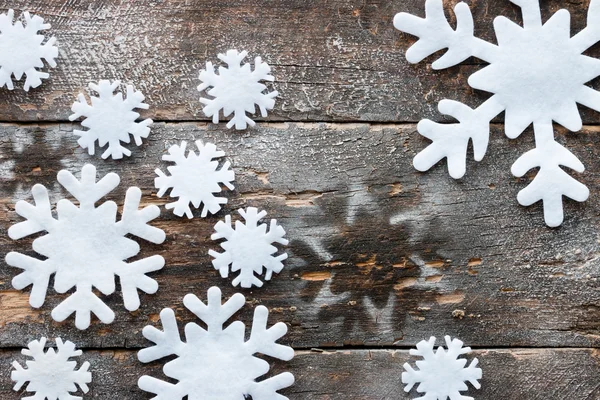 Flocos de neve artificiais em um fundo de madeira — Fotografia de Stock