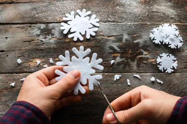 Homem esculpe um floco de neve em um fundo de madeira — Fotografia de Stock