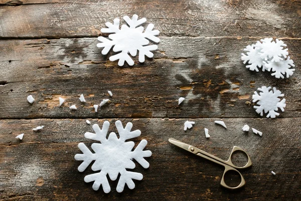 Flocos de neve esculpidos e tesouras no fundo de madeira — Fotografia de Stock