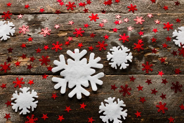 Flocos de neve esculpidos e ouropel vermelho em um fundo de madeira — Fotografia de Stock