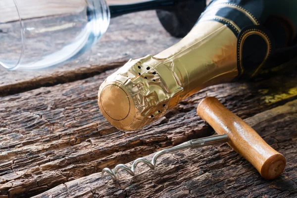 Kurkentrekker en een fles champagne glas liggend op de houten achtergrond — Stockfoto
