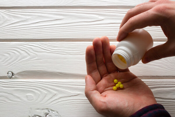man takes ascorbic acid on a white background