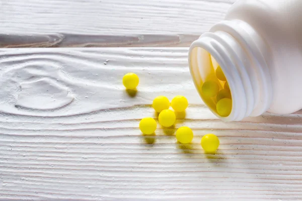 Ascorbic acid is poured out from packing on a wooden background — Stock Photo, Image